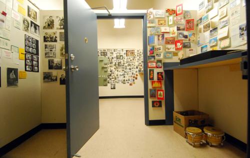 A small room with door open. all walls are cover with various give artifacts (like photos and cards) and organized neatly.