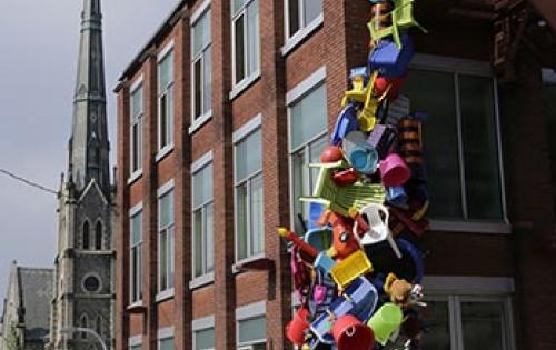Building with a variety of plastic colourful objects crawling up the corner of it. 