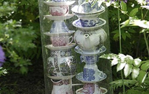 Teacups stacked on top of each other in a plastic covering placed in a garden. 