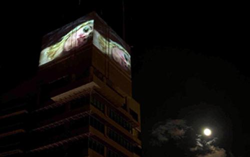 Large screens on top of building playing video of woman kissing camera