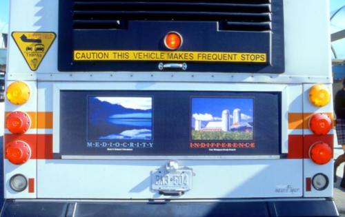 back of bus with two images one of a lake the other a farm with text that read mediocracy and indifference
