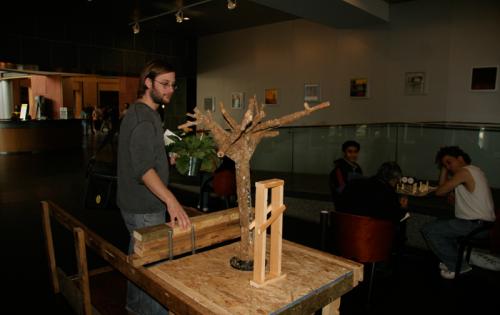 Man interacting with sculpture which features a small leafless tree