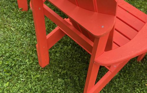 Vibrant red Muskoka chairs on a clover lawn