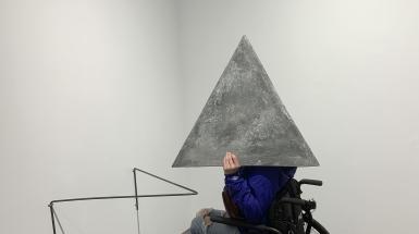 a person in a wheelchair wearing the triangular concrete helmet