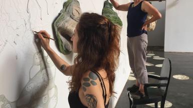 ZAC members collectively drawing on a white wall interspersed with objects