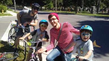 Group of people posing with bikes and helmets on as past Alley Cat participants.