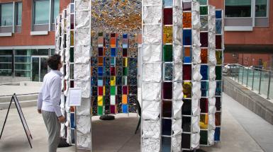 A youth admiring a large sculpture of multicoloured cloth mosaics.