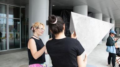 The artist demonstrating to a participant how to put the pyramid on to listen to it.