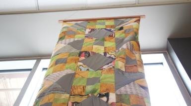 The top of the patchwork quilt hanging.