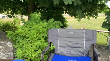A square folding camp chair and stool with blue cushions to match.