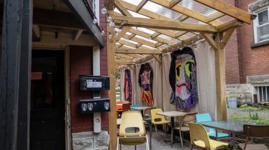 View of three woven faces hung outdoors at the Yeti Cafe.