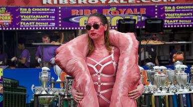 The artist is posing in front of BBQ trophies at Ribfest.