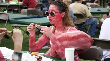 The artist is sitting at a table eating ribs.