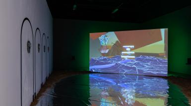 A projected video reflected in a silver floor, fours mirror masks placed along the left wall.