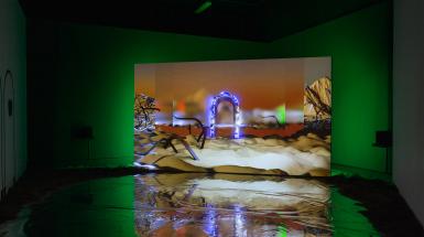 A scene from the projected video showing a glowing purple arch amid an alien sandy landscape.