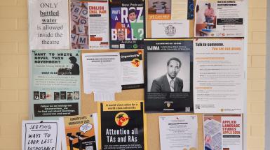 A poster that says "Seeking ways to look less disposable" among other posters on a cork board.