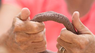 Two hands sculpting a clay ring.