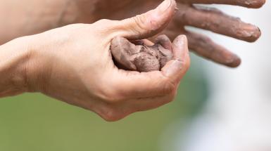 Two hands squeezing a ball of clay.