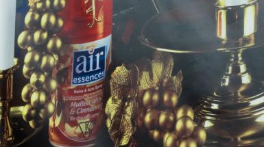Closeup of shiny items arranged in still life - a red can of air freshener, golden grapes, a golden candelabra, and a golden platter