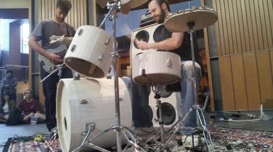 Two musicians one playing drum and another playing guitar. 