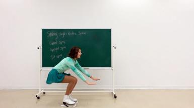 Artist squatting wearing skates in front of chalkboard.