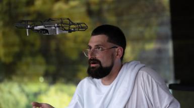 Artist flying small drone with hands outreached.