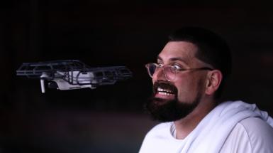 Artist smiling nervously with drone flying in front of his face. 