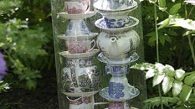 Teacups stacked on top of each other in a plastic covering placed in a garden. 