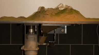 A machine holding up a diorama of a mountain. 