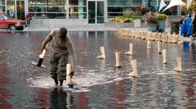 a man placing wooden feet in shallow man made pond. 