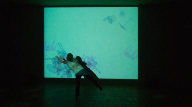 A woman standing in front of a colourful projection