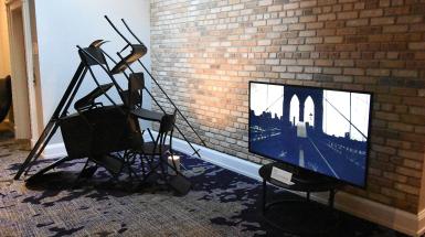 On the left chairs staked to for a tent like structure. On the right a Tv which is playing a video of a bridge.