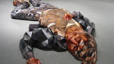 A sculpture of a man laying down. Using geometric shapes to create the figures shape.