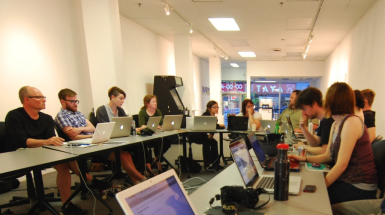 Individuals around a table look at laptops
