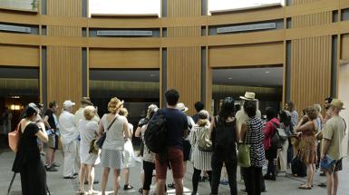 back of crowd standing and watching someone talk