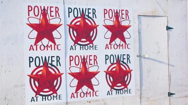 a series of ads that mix communist iconography and images of hydro electricity. 6 posters on wall each say power on top. 3 say at home on the bottom. 3 say atomic at the bottom. With red stars in the center. 