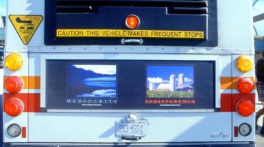 back of bus with two images one of a lake the other a farm with text that read mediocracy and indifference
