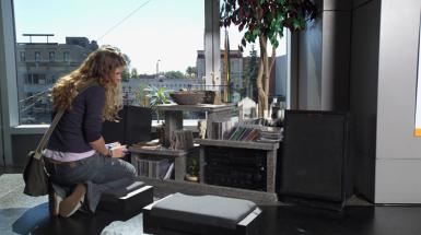 A woman crouching beside a radio shelving unit made of granite. 