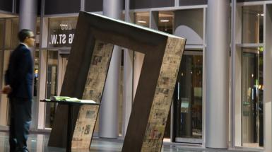 Man in suit observing titles rectangular sculpture