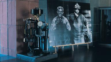 Image of metal machine beside photograph of two blue collar workers