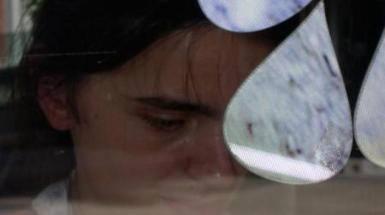 Person crying with three water droplet shapes project on glass in front