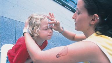 Woman putting temporary tattoo on child's forehead
