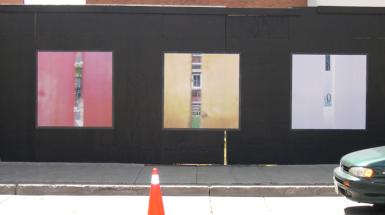 Three photographs on wall that have colour on ether side with sliver that show a building through it. 