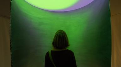 Figure looking up a circular room filled with green light