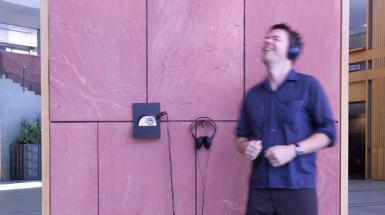 Person listening to Disc-man which is suspened from wall. Seems to be dancing