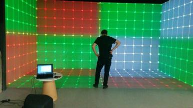 Jesse standing in the hive whit is a room with coloured lit up walls