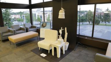 A chair, side table, plants and lamp with bird on top made of paper