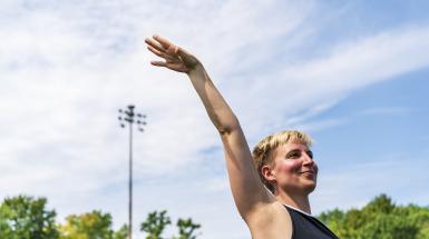 A woman with her right arm up in the air palm down.