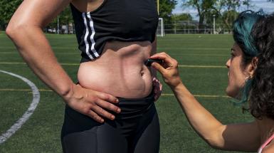 Someone drawing abdominal muscle lines on the tensed abs of another person