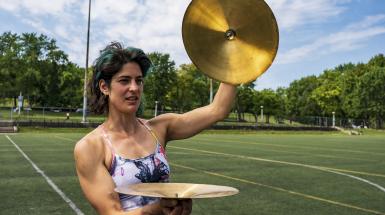 A woman preparing to crash together a set of cymbals